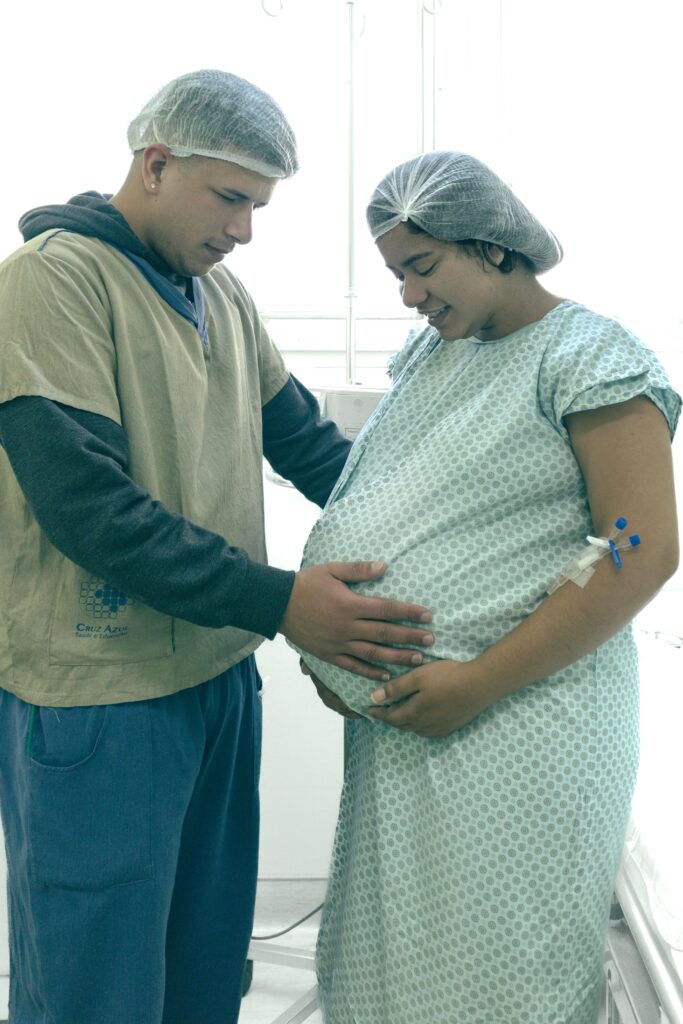 Pregnant woman and partner in hospital, embracing parenthood.