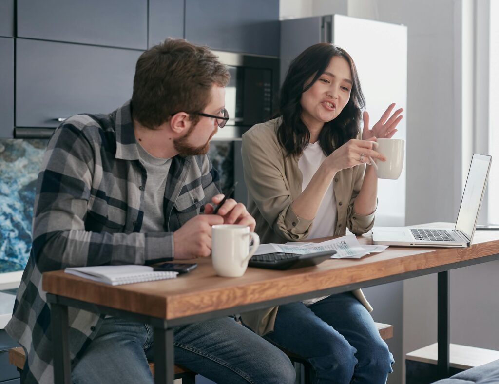 A couple having a discussion with coffee and laptops, reflecting relationship communication indoors.