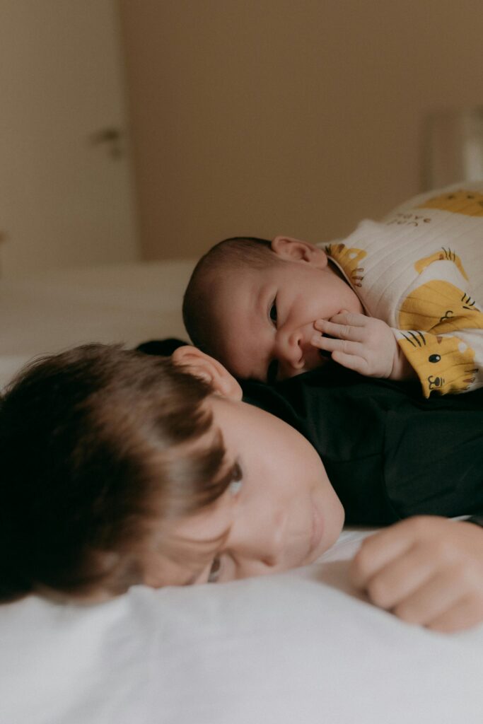 A loving moment between a baby and child siblings on a cozy indoor bed.