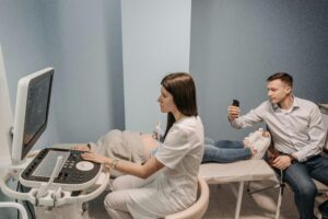 Medical professional conducts ultrasound for expectant couple in clinic.