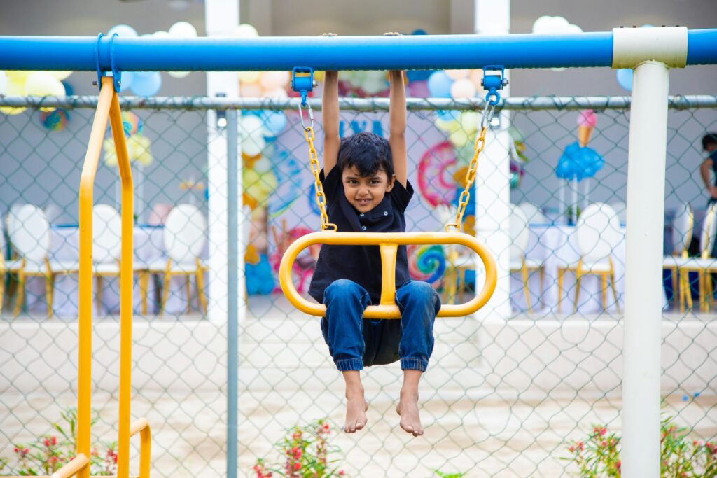 Un alegre niño colgado de un columpio durante una sesión de juego diurna al aire libre.