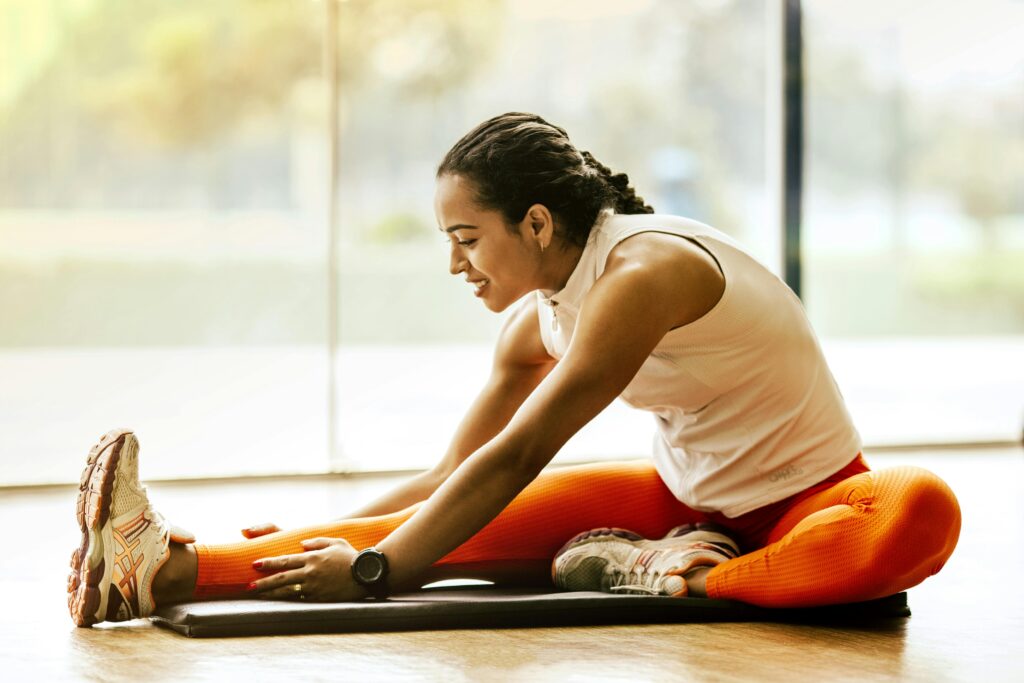 Una mujer disfruta de un estiramiento de yoga en el interior, promoviendo un estilo de vida saludable.
