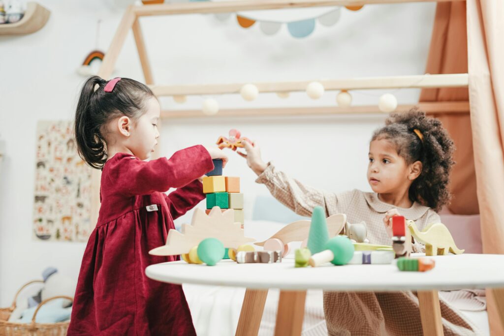 Dos niñas disfrutan jugando con juguetes de madera en el interior de una cálida y colorida sala de juegos.