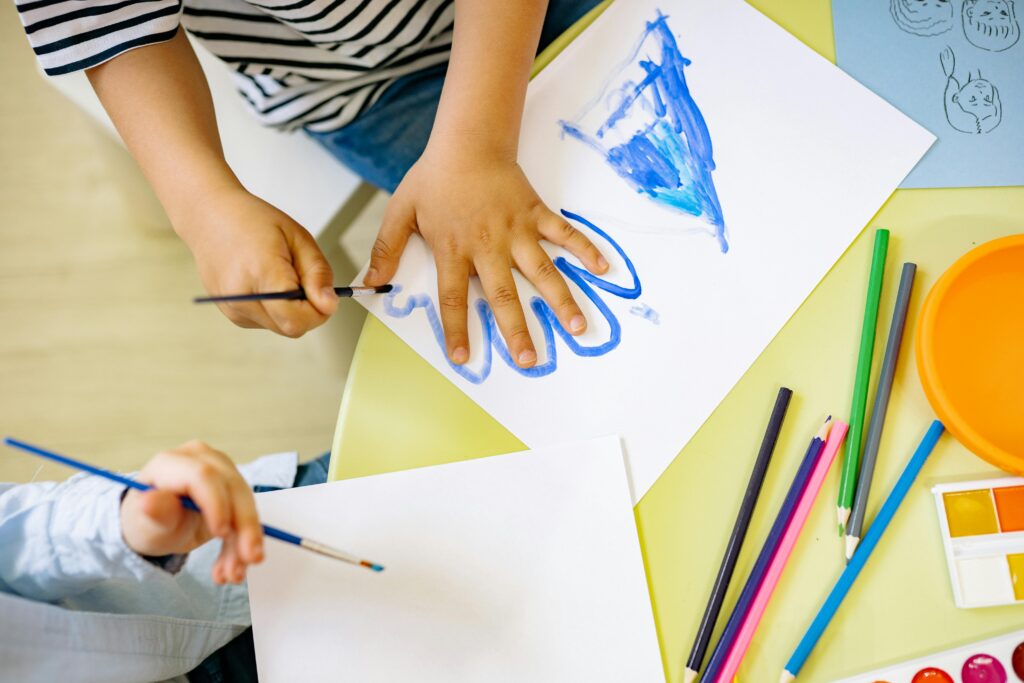 Los niños pintan con acuarelas y lápices de colores, fomentando la creatividad y el aprendizaje en un entorno divertido.