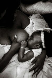 Artistic black and white photo of a mother breastfeeding her baby, showcasing tenderness and intimacy.