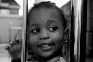 Adorable portrait of a smiling child in black and white, showcasing innocence and joy.