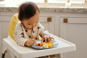 A cute toddler in a polka dot outfit enjoying a healthy fruit snack indoors.