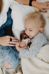 A young child relaxing indoors, hugging a stuffed animal with a sense of comfort and warmth.