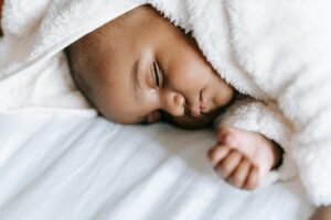 A serene infant sleeping soundly wrapped in a cozy blanket, conveying tranquility.