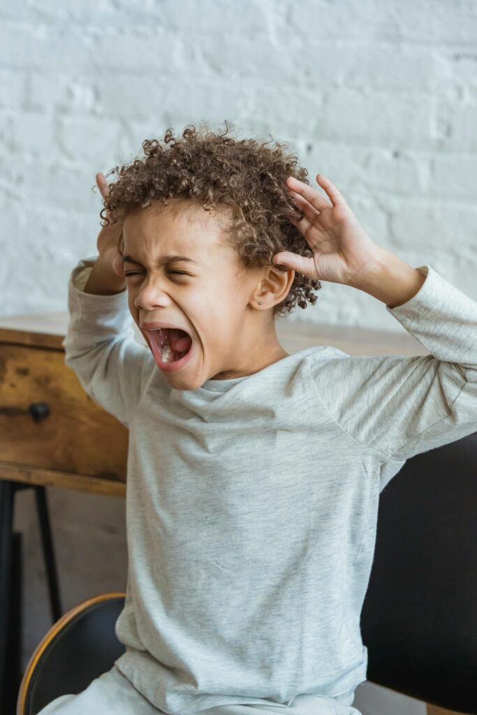 Niño negro mostrando frustración en un interior, con las manos en la cabeza en señal de angustia.